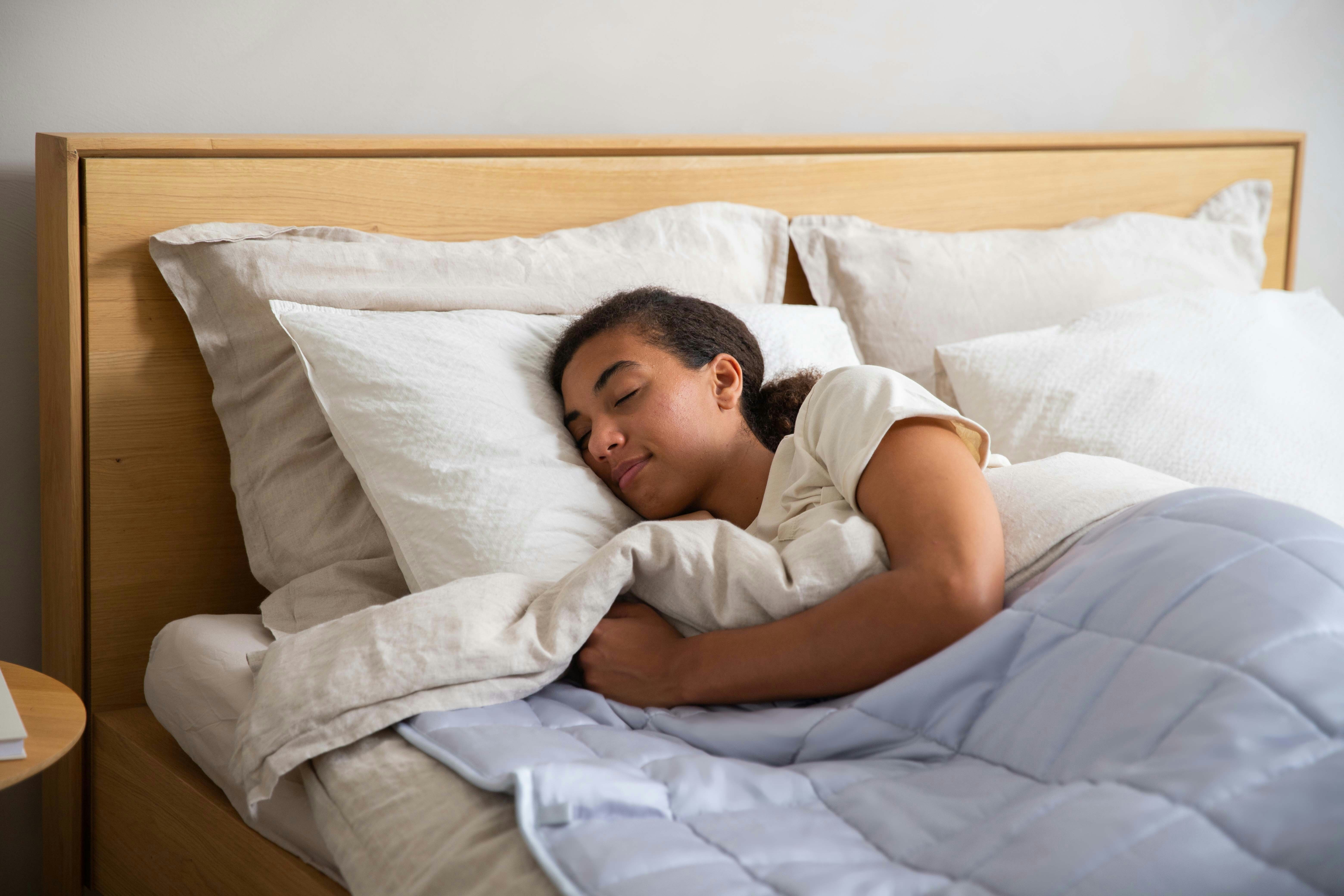 A teenage athlete asleep in bed in the early morning with training kit laid out nearby — the recovery window most youth sport and school schedules quietly compress.