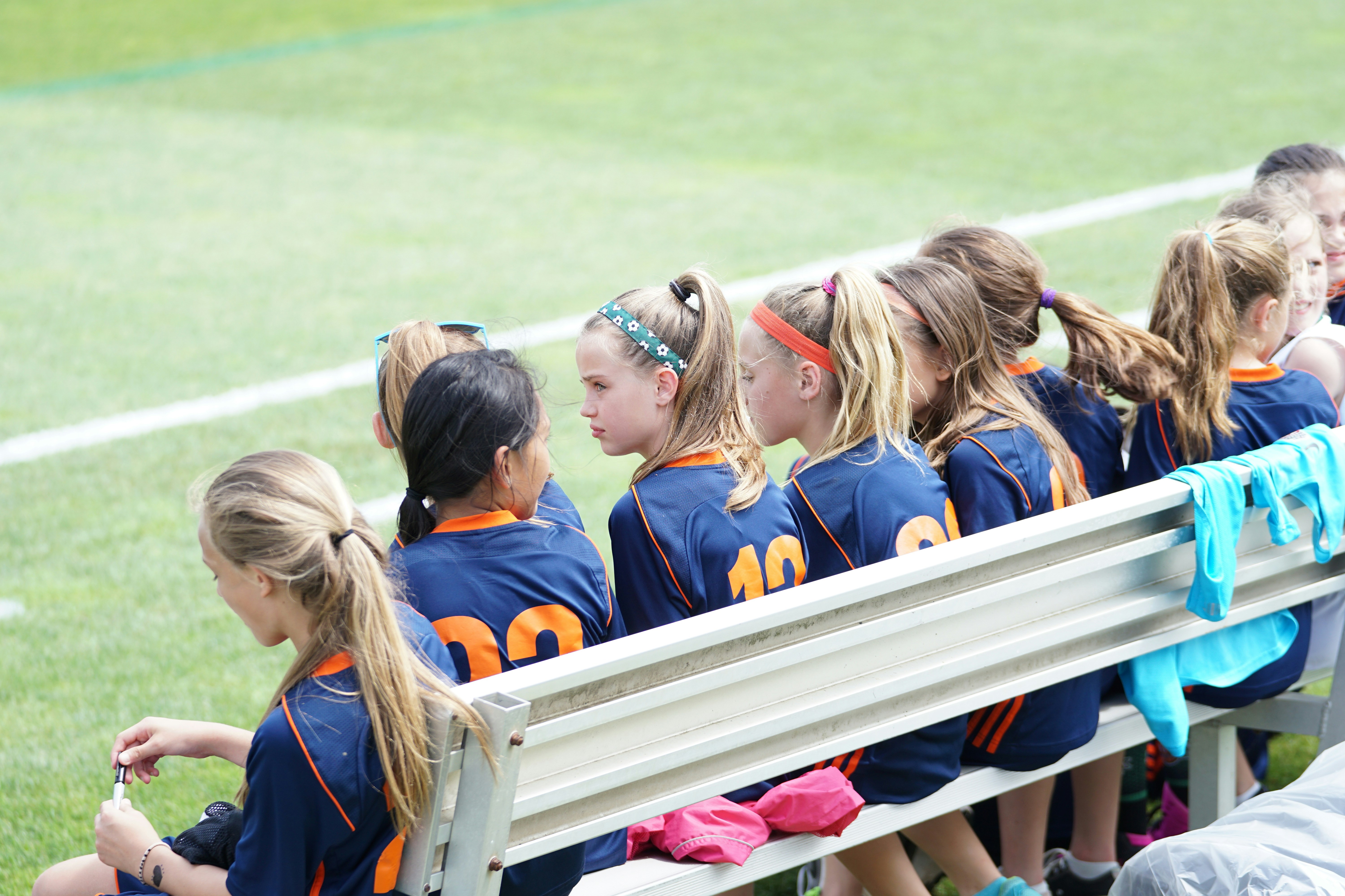 A parent watching a young athlete from the sideline during a match — supportive presence without sideline coaching is what the sport psychology research on parental involvement actually favors.