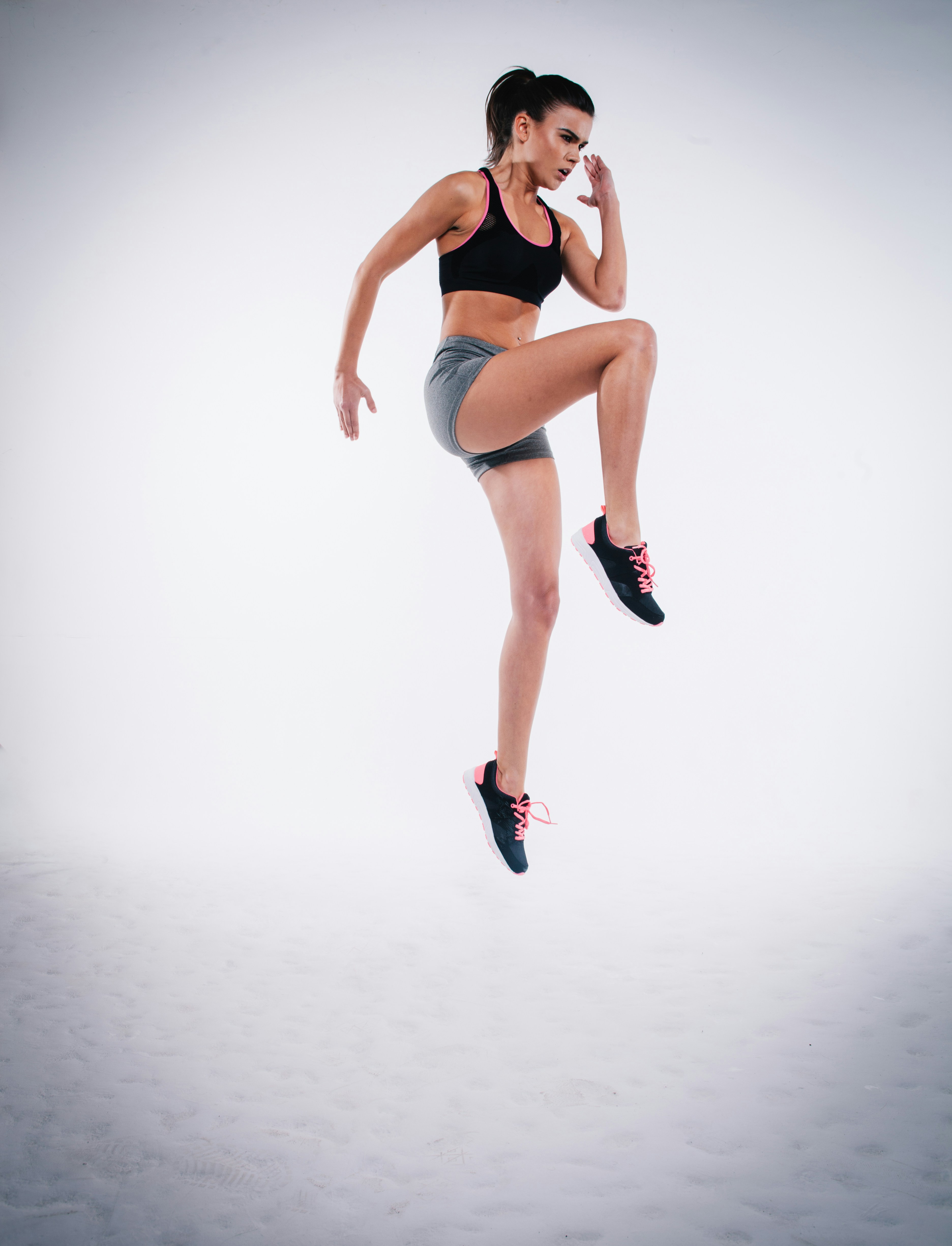 An athlete performing a countermovement jump on a dual force plate system, with force-time data displayed on a laptop screen beside the platform.