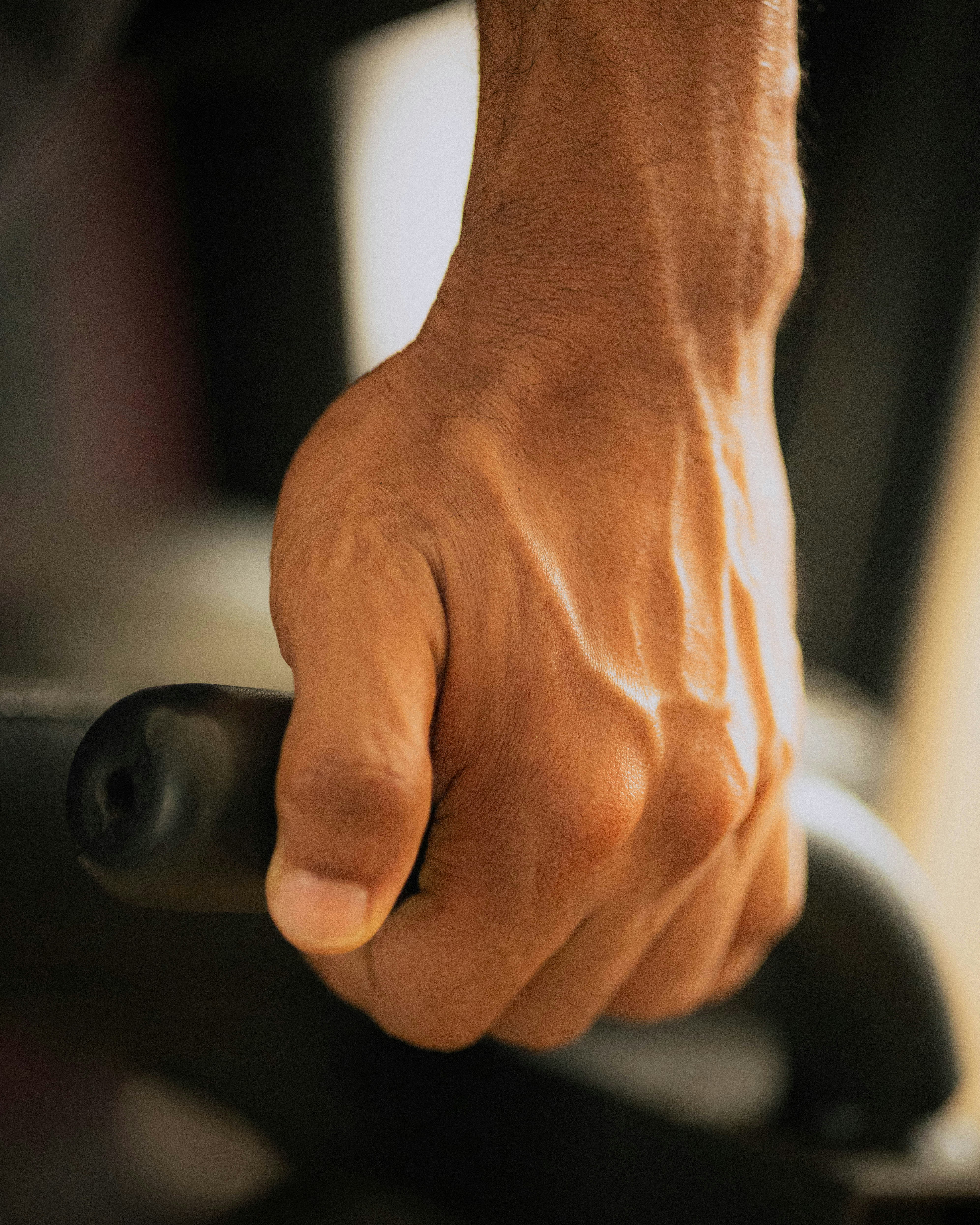 A close-up of a hand gripping a hand dynamometer during a strength test — grip strength has become one of the most heavily studied predictors of mortality and overall health in exercise science.