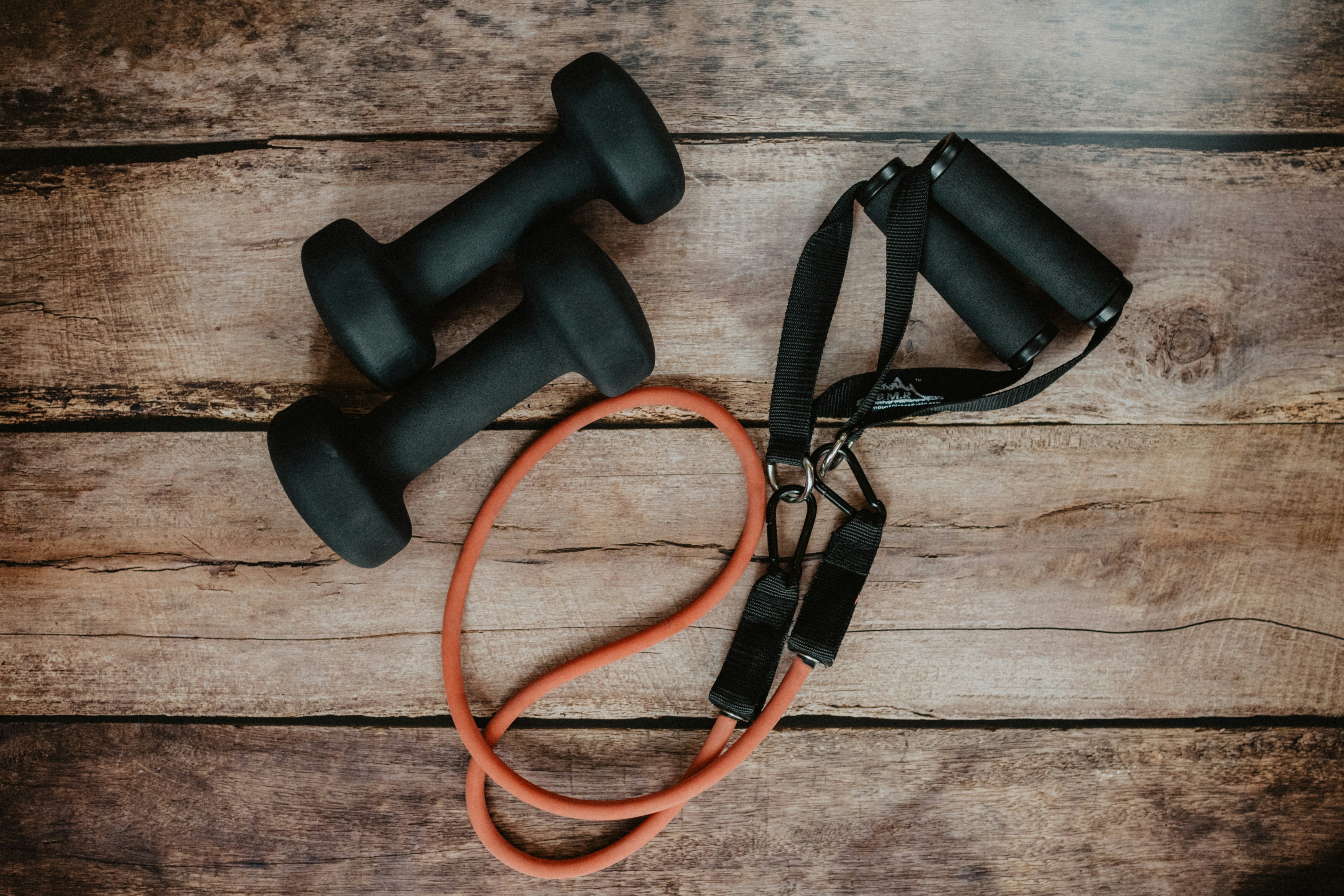 A small home training corner in an HDB living room — resistance bands, a jump rope, and interlocking mats laid over the tile, close to the actual footprint a young athlete's home setup needs.