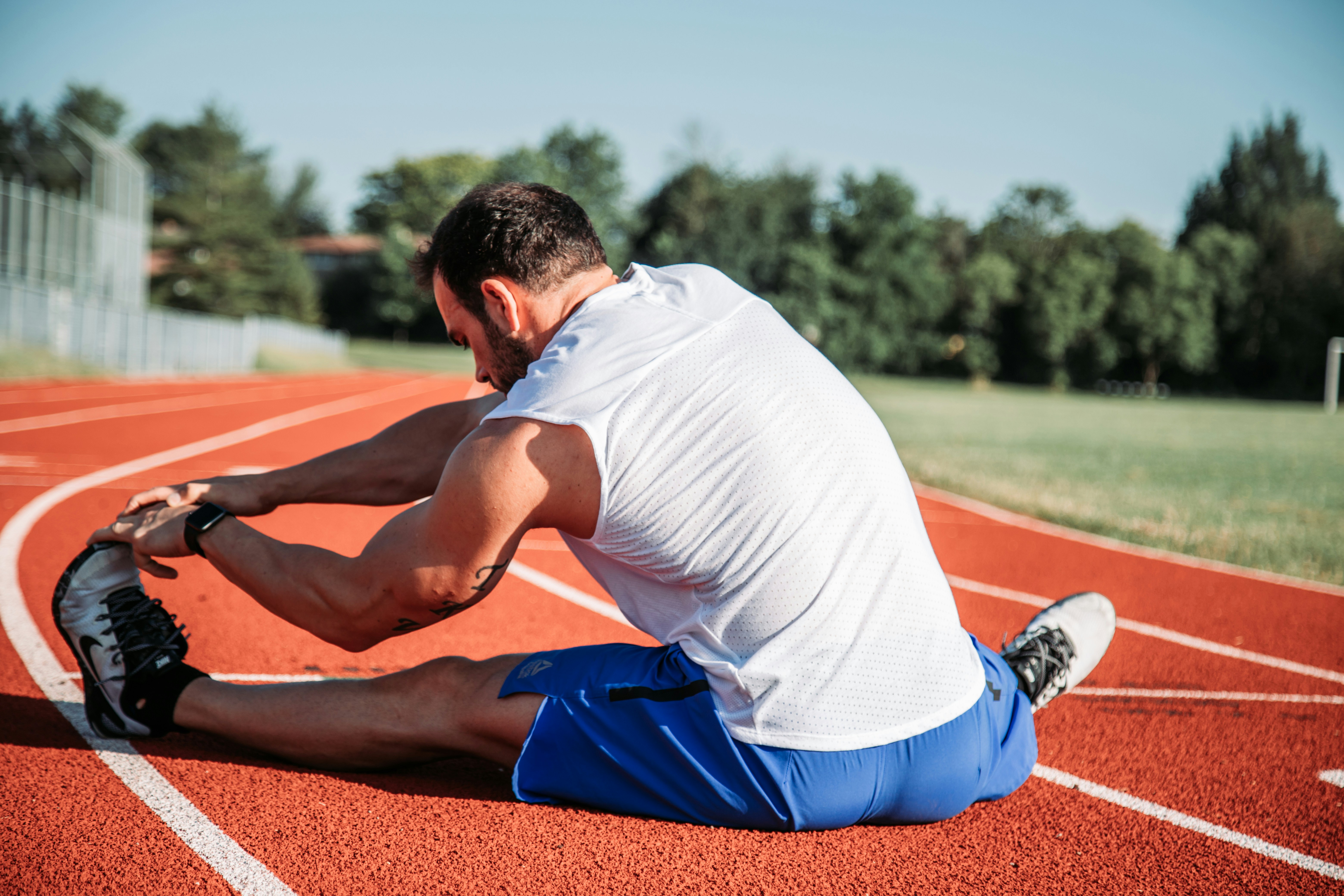 A coach guiding an athlete through a controlled, loaded mobility drill at end-range — active control through range of motion, not passive stretching, is what the research links to performance and injury outcomes.