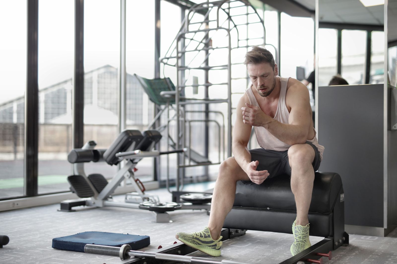 An athlete sitting on gym equipment, visibly fatigued, catching his breath after a training session — the kind of moment every overtraining-monitoring tool is trying to predict before it happens.