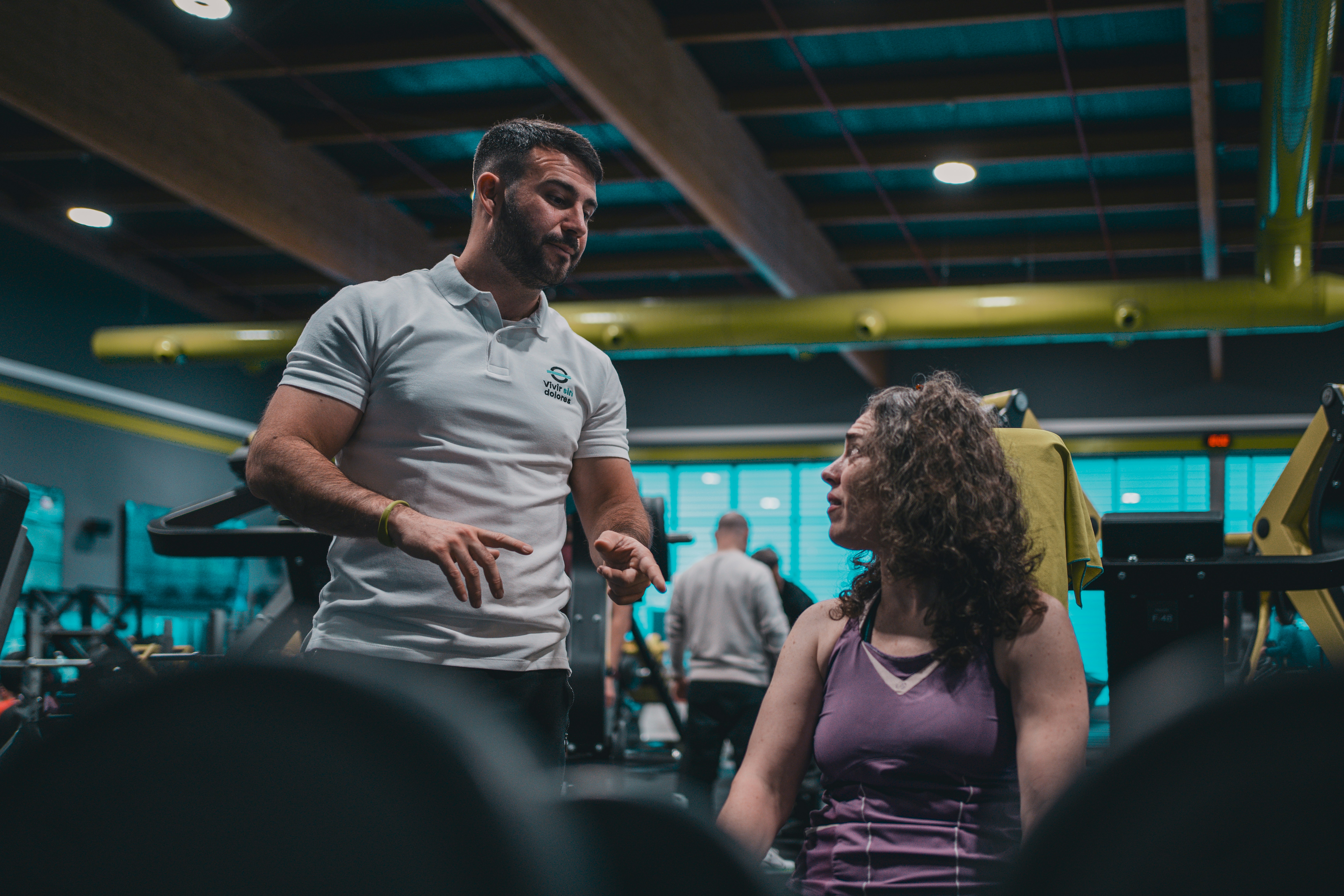 A physical education teacher and a specialist strength and conditioning coach conferring on a school sports field before a session