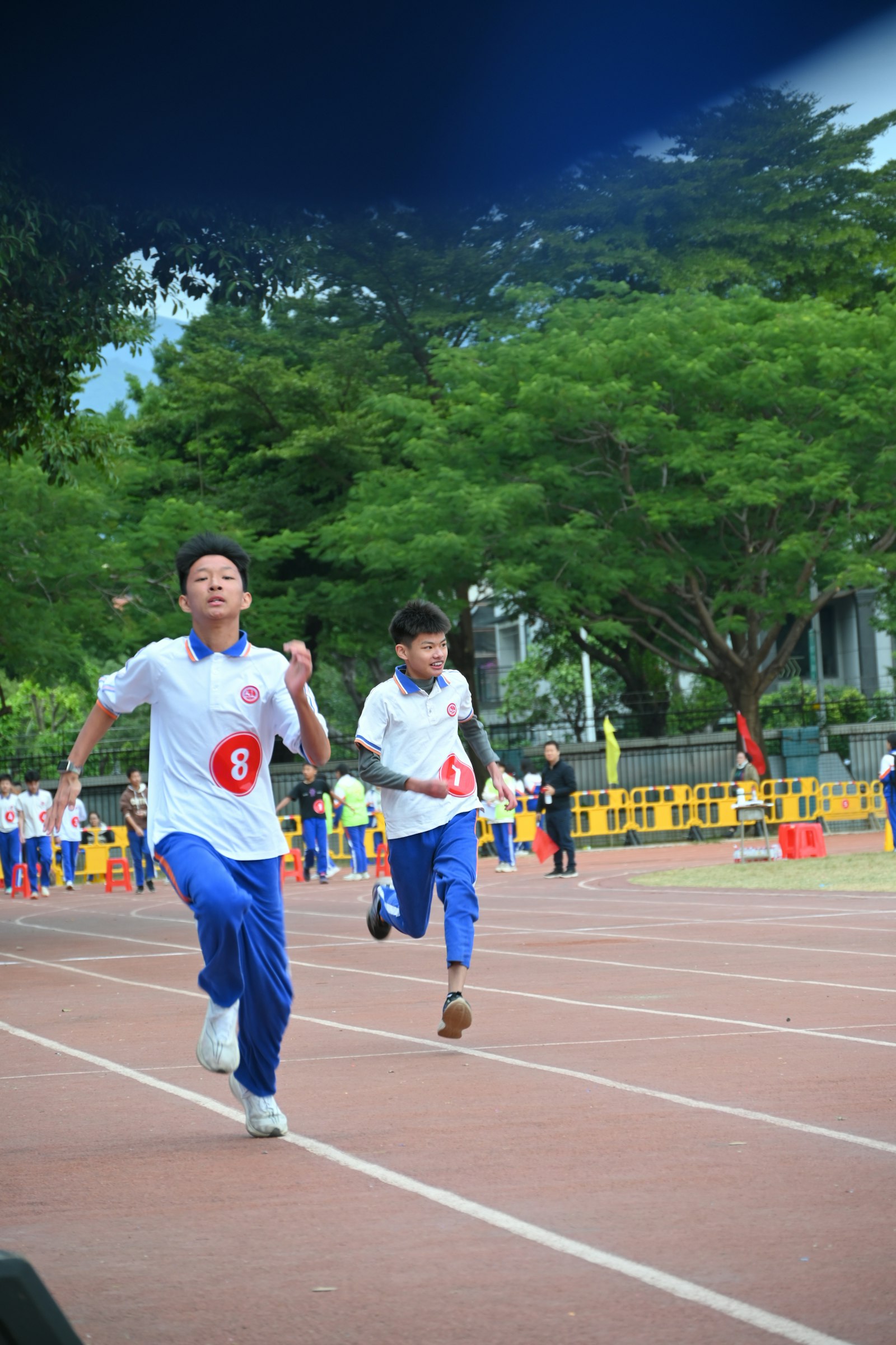 Two young boys sprinting mid-race on an outdoor running track — a fitness test like this is one of several things a good PE program is supposed to measure, not the whole picture.