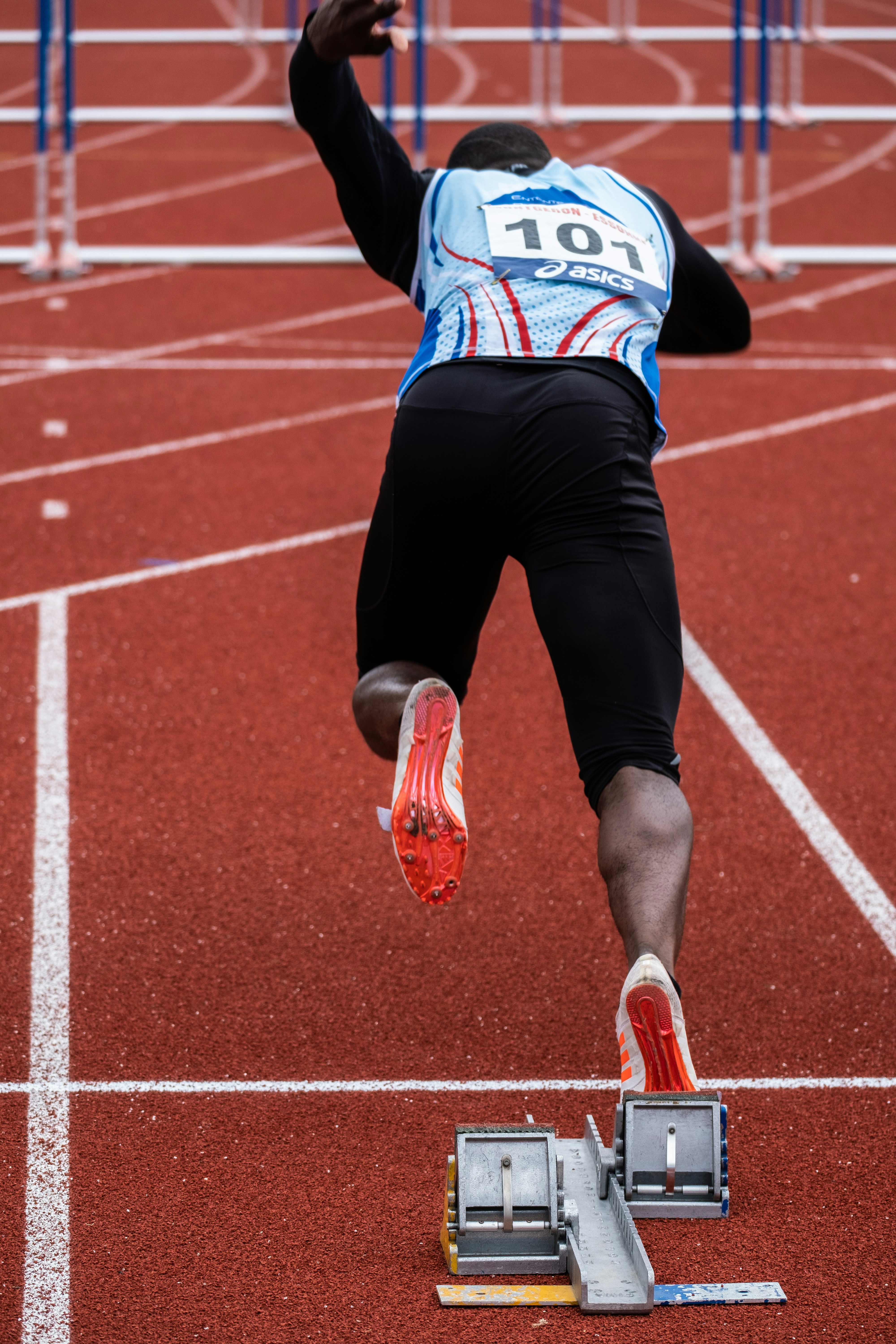 A young athlete pausing to reset after a tough play while a coach looks on — the kind of moment sport psychology research treats as a trainable skill, not a fixed personality trait.