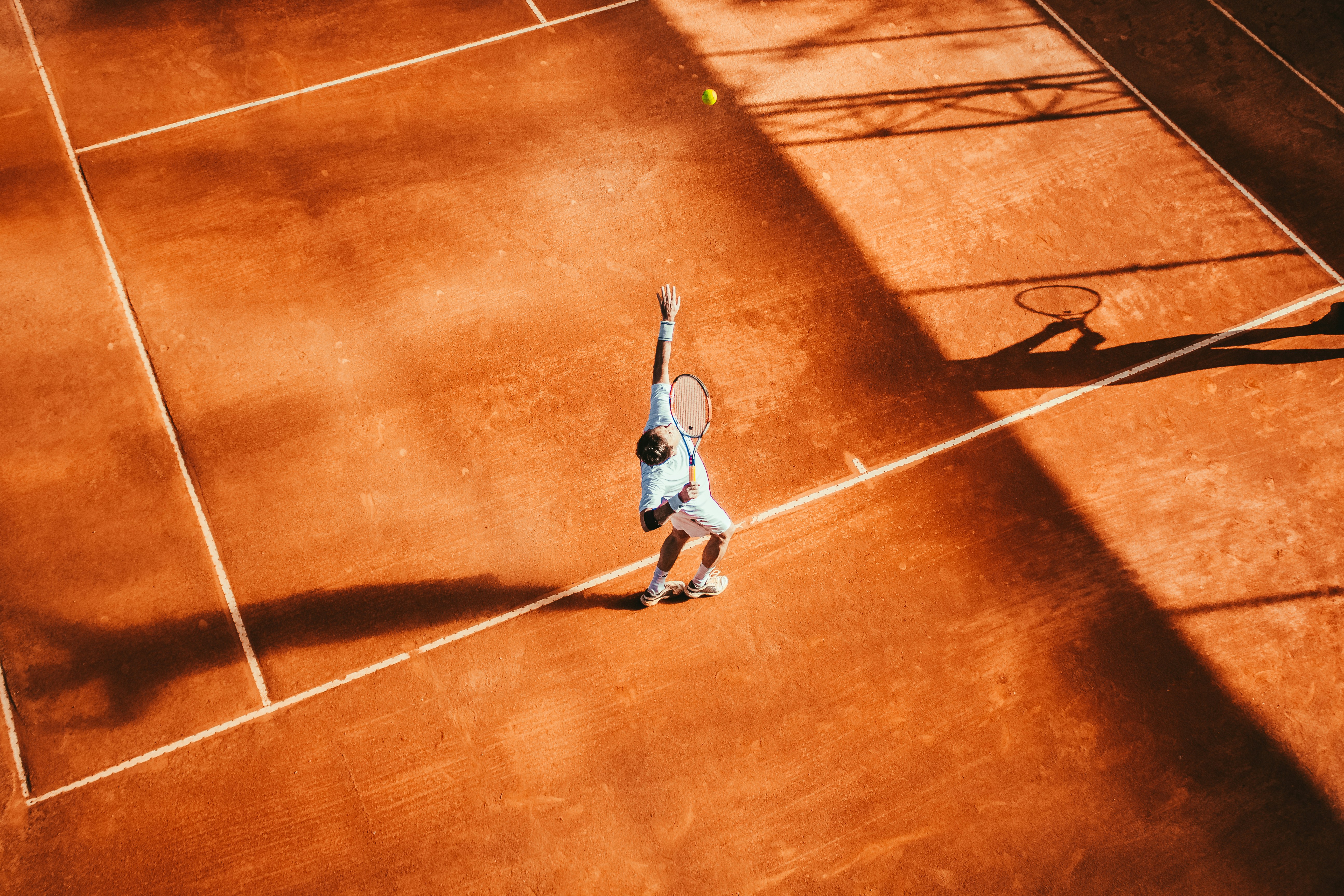 A young tennis player mid-serve on an outdoor court — the repetitive overhead motion at the centre of the shoulder, elbow, and wrist overuse injuries covered in the research below.