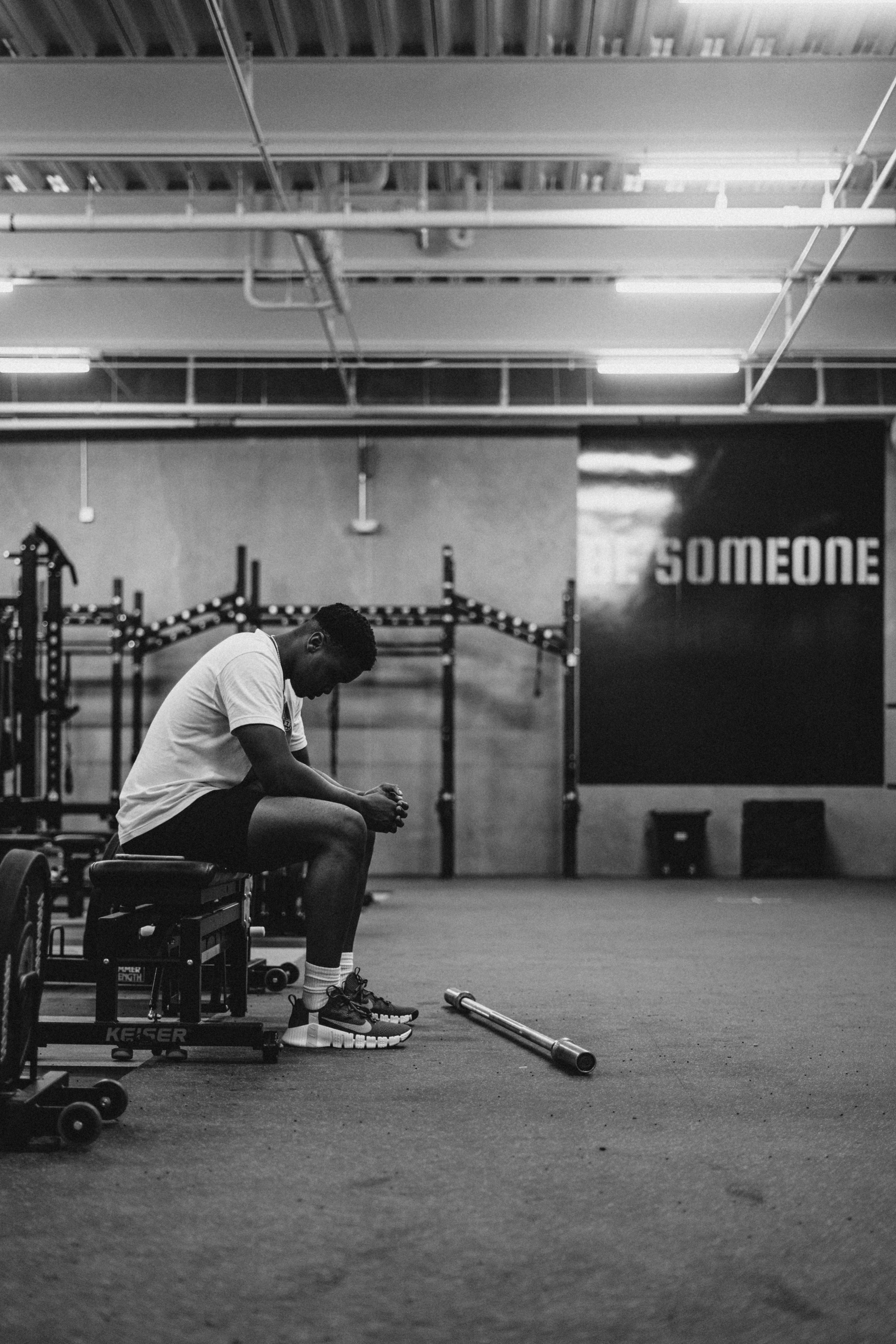 A tired athlete sitting on the floor of a gym catching their breath after a session — the moment the session-RPE research asks a coach to collect a single number, and the research says that number holds up remarkably well against expensive lab equipment.