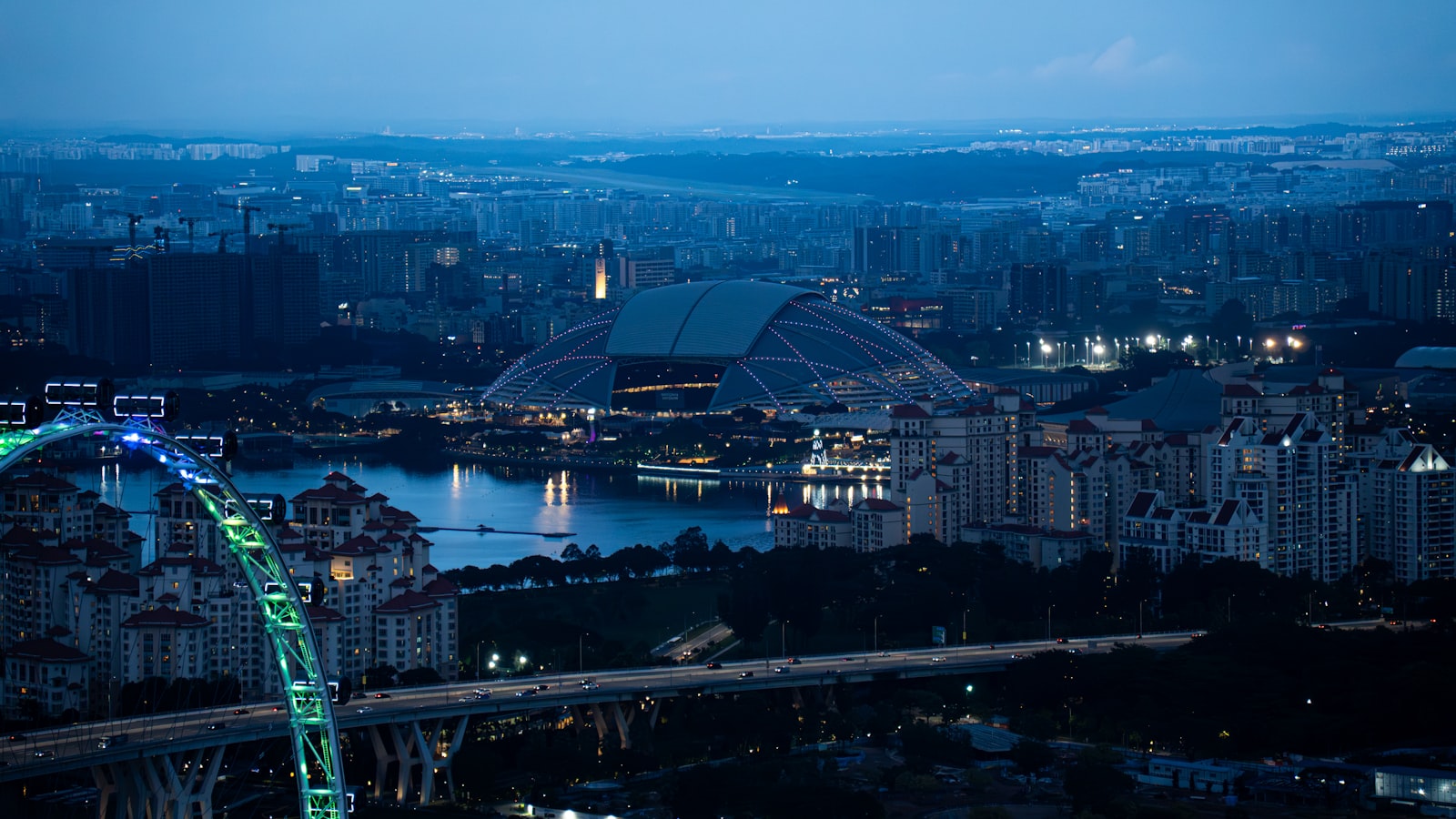 Aerial view of Singapore's National Stadium and Sports Hub at dusk, beside the Kallang river.
