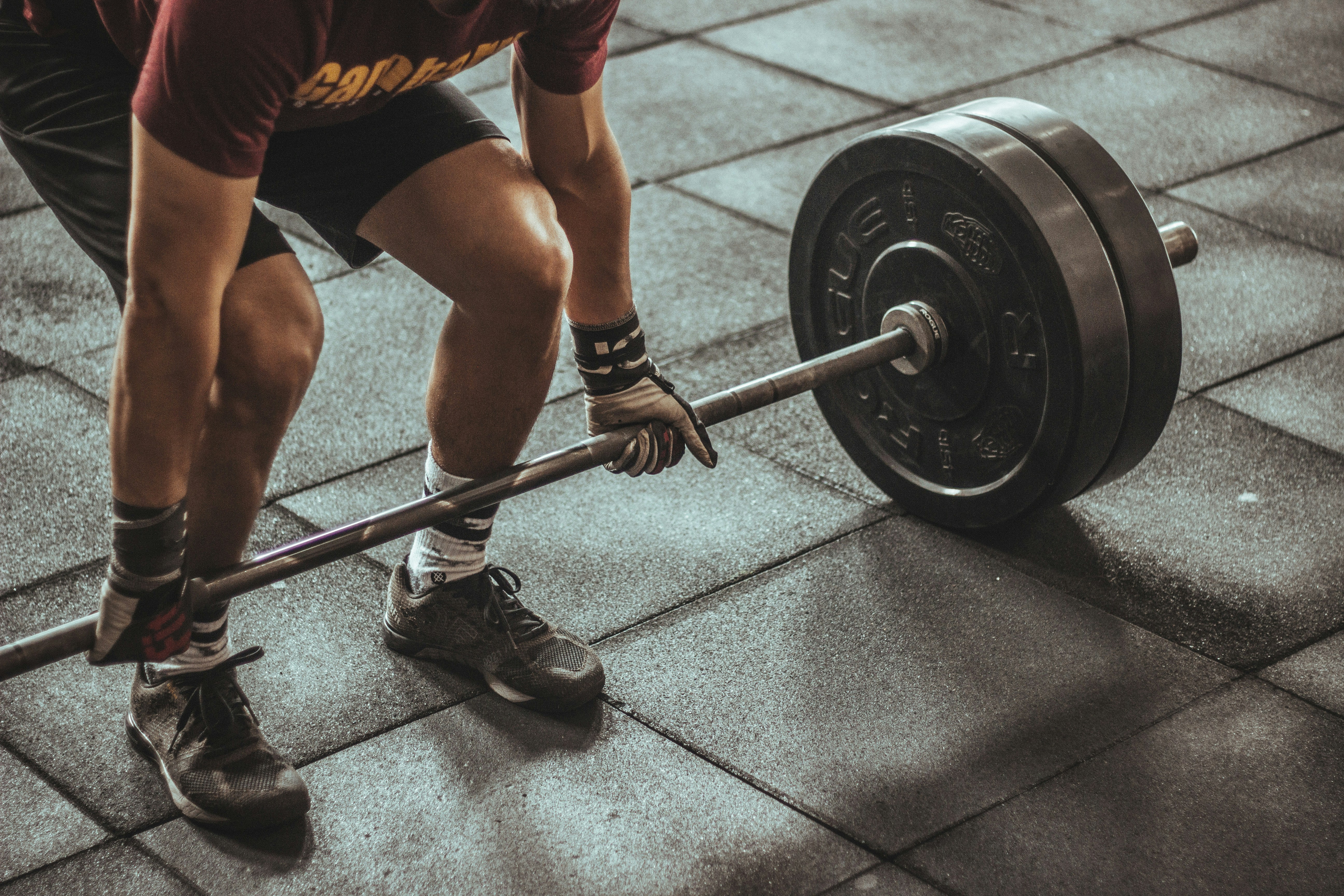 A teenage athlete performing a coached barbell back squat in a training facility — the evidence says training age and biological maturity, not a chart of adult strength standards, should set the benchmark.